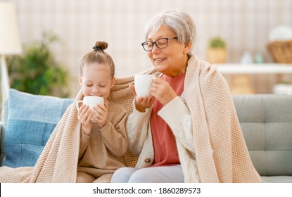 A nice girl and her grandmother enjoying warm beverages. Good time at home. 