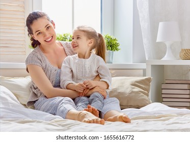 A nice girl and her mother enjoying sunny morning. Good time at home. Child wakes up from sleep. Family playing on the bed in the bedroom.   - Shutterstock ID 1655616772