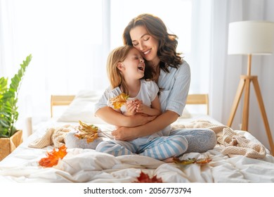 A nice girl and her mother enjoying sunny morning. Good time at home. Child wakes up from sleep. Family playing on the bed in the bedroom. - Powered by Shutterstock