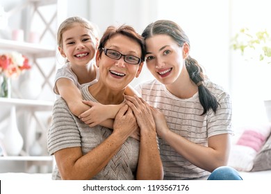 A nice girl, her mother and grandmother enjoy sunny morning. Good time at home. Family playing in the bedroom.