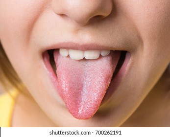 Nice Girl Showing Her Tongue. Child Puts Out Tongue - Close Up.