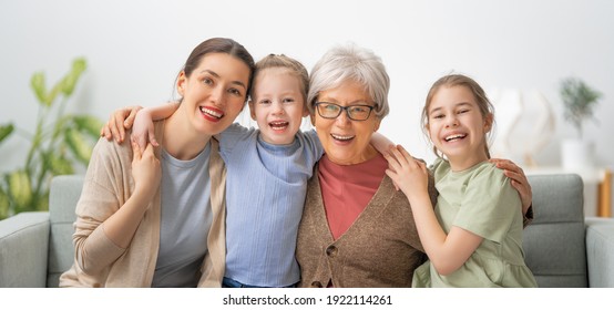 A nice girls, their mother and grandmother are hugging and  enjoying spending time together at home. 