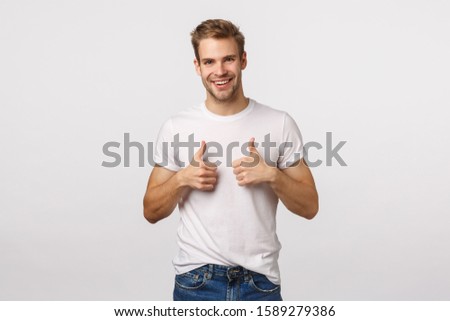 Nice job, congratulations. Happy and satisfied good-looking blond guy with bristle show thumbs-up in approval, like or recommendation gesture, smiling pleased, agree, encourage friend made good job