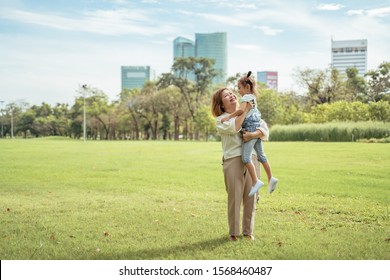 Nice Little Girl Run To Grandmother's Hug In Park.Grandmother And Grand Daughter Enjoying Sunny Garden Holiday Together, Outdoors Space, Leisure Lifestyle,happy Teaching With Flare Light Sky In Park.