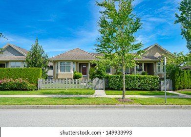 Nice looking house behind the green and wooden fence at the empty street in the suburbs of Vancouver, Canada.