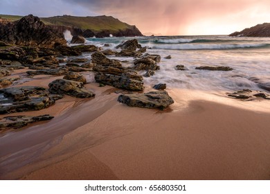 Nice looking landscape view of the agitated ocean, rocks, sunset and incoming, imminent rain.