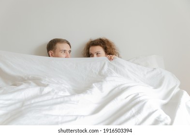 Nice looking young couples slept together, covered their faces with blankets and looked at each other. - Powered by Shutterstock