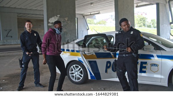 Nice\
mood cheerful cops let out black man offender dance together with\
funny cool moves in front of the police patrol\
car.