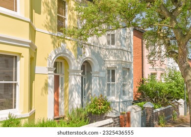 Nice Neighbourhood. Colorful pastel terraced houses in a row, in classic architectural English style, with trees at the street. Diversity concept. Dream upper middle-class community.