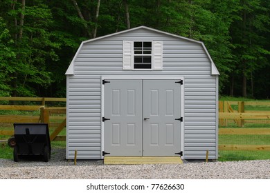 A nice new storage shed outside of a fenced in  back yard with a trailer beside it with room for your text.