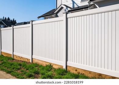 Nice new wooden fence around house. Wooden white fence with green lawn. Street photo, nobody, selective focus
