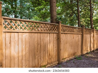 Nice new wooden fence around house. Wooden fence with green lawn in a sunny summer day. Street photo, nobody. Beautiful wooden fence around the house. Solid cedar fence - Powered by Shutterstock