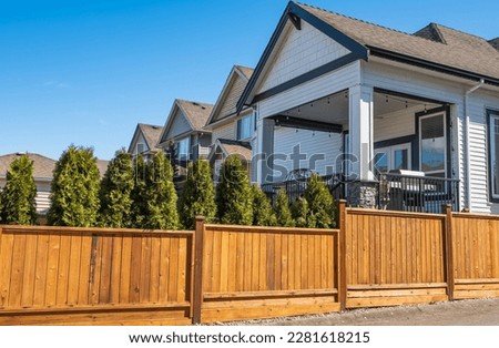 Nice new wooden fence around house. Wooden fence. Street photo, nobody, selective focus. Real Estate Exterior Front House on a sunny day