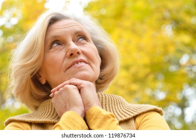 Nice Older Woman Stands On A Background Of Yellow Autumn