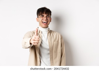 Nice One. Happy Young Man Laughing And Showing Thumb Up, Like Something Good, Standing On White Background, Complimenting You