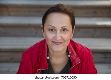 Nice Portrait Of Middle Aged Older Woman. Professional Headshot Of 45 50 Year Old Woman Looking At The Camera And Smiling. Close Up. Blurred Outdoor Background.