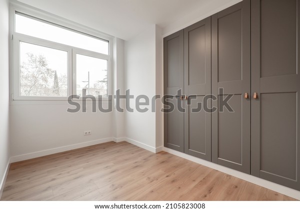 Nice room with large window, pine wood\
floors and built-in wardrobes with gray\
doors