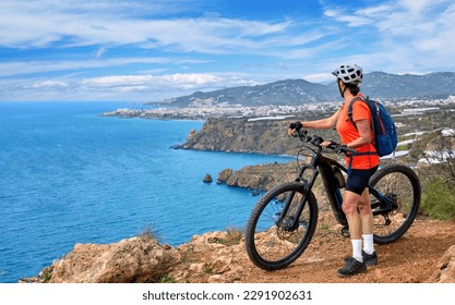 nice senior woman cycling with her electric mountain bike at the Costa Blanca coastline near Nerja, Andalisia, Spain - Powered by Shutterstock