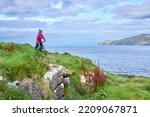 nice senior woman on mountain bike, cycling on the cliffs of Dunmore Head near Kilballyowen , County Limerick in the southwestern part of the Republik of Ireland