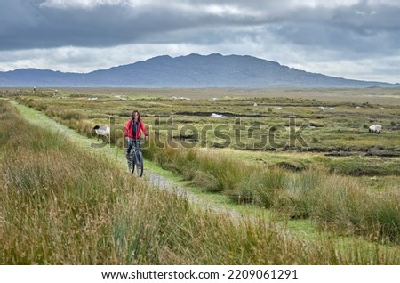 nice senior woman on mountain bike, cycling bog Area near Derrycunlagh, County Galway, in  the western part of the Republic of Ireland
