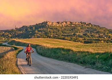 nice senior woman riding her electric mountain bike between olive trees in the Ghianti area with Montepulciano in background, Tuscany , Italy - Shutterstock ID 2220192491