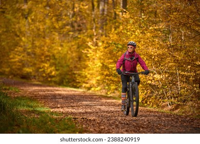 nice senior woman riding her electric mountainbike on the autumnal forest trails near Stuttgart,  - Powered by Shutterstock