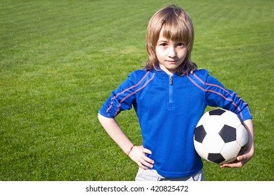 Nice smiling happy 8 years old boy stand with volleyball ball in the park field outside on sunny summer day