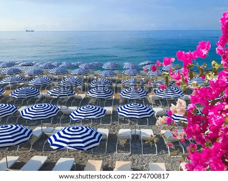 Nice stone beach and turquiose water of cote dAzur at summer morning with open traditional umbrellas, french riviera coast