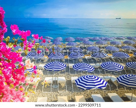 Nice stone beach and turquiose water of cote dAzur at summer morning with open traditional umbrellas, french riviera coast
