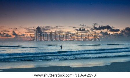 nice sunrise over florida atlantic ocean with fisherman silhouetted in surf