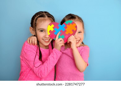 Nice sweet funny little sister girls are holding a card with puzzle pieces inside - symbol of autism. Support the unity of humanity - Powered by Shutterstock