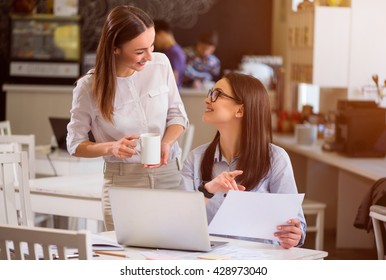 Nice talk. Cheerful delighted smiling woman sitting at the table and talking with her colleague who is drinking coffee - Powered by Shutterstock