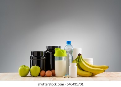 Nice Variant Of Nutrition For Staying Fit And Healthy. Great Set Of Amino Acid Complex, Protein And Creatine For Sportsmen. Fresh Fruits And Three Eggs With A Bottle Of Mineral Water On The Table.