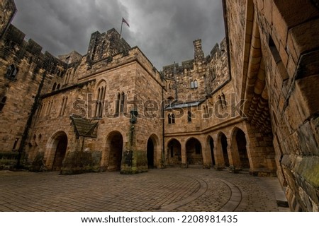 Nice view of an inner courtyard of alnwick castle under a grey overcast and threatening sky, in england