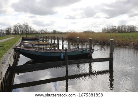 Nice view over a small rural Dutch harbor with small iron rowing boats. Photo was taken at the beginning of spring.