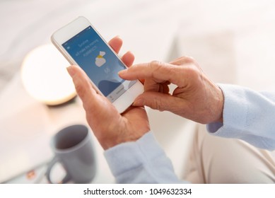 Nice Weather. The Close Up Of The Hands Of An Elderly Woman Holding A Phone And Checking The Weather App Showing Nice Forecast