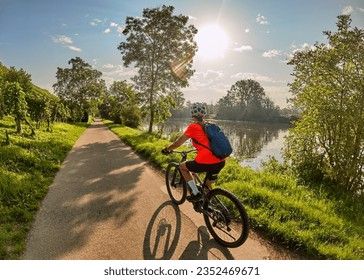 nice woman with electric mountain bike, cycling in moody morning light on the Neckar valley bicycle path near Ludwigsburg, Baden Württemberg, Germany - Powered by Shutterstock