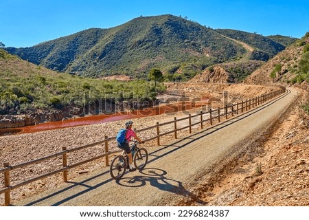 nice woman with electric moutain bike on a bike tour along river Rio Tinto with its natural red water in Andalusia, Spain