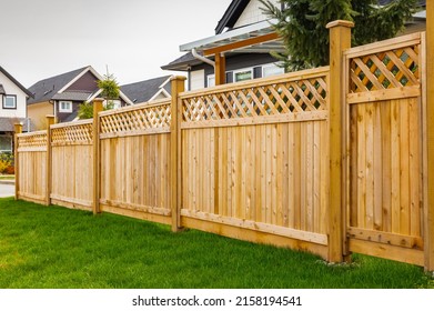 Nice wooden fence around house. Wooden fence with green lawn. Street photo, nobody, selective focus