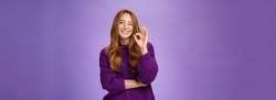 Nice Work You Did Great. Satisfied And Happy Charming Assertive And Supportive Redhead Woman In Purple Sweater Smiling And Winking In Approval Showing Okay Gesture, Liking Product Over Violet Wall.