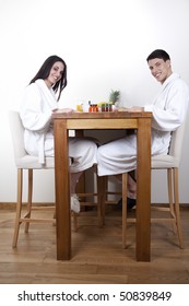 Nice Young Couple In The Morning Eating Their Breakfast In Their Home, Wearing White Towel Robe.