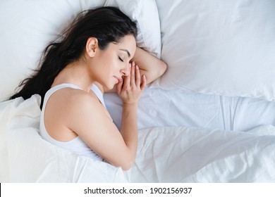 Nice-looking caucasian young girl sleeping in her comfortable bed with white linen