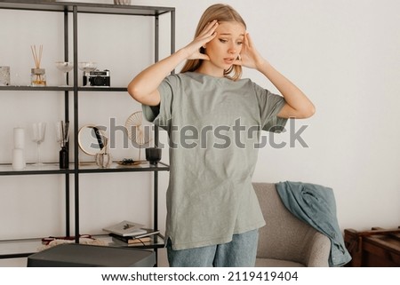 Nice-looking girl in a grey t-shirt is panicking before moving to another country. The girl leaves her apartment
