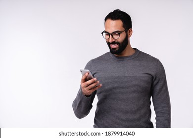 Nice-looking young Arabian man in casual clothes using mobile phone isolated over white background