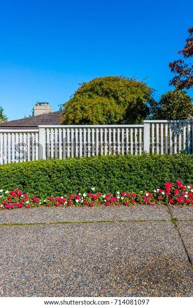 Nicely trimmed bushes and flowers in front of the\
fence. Separate and protect private property. Keeps privacy and\
security. Landscape\
design.