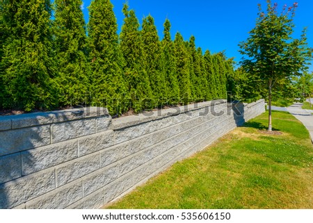 Nicely trimmed bushes on the leveled and stoned front yard. Green fence. Keeps privacy and security. Landscape design.