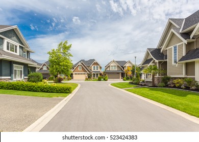 Nicely trimmed and manicured garden in front of a luxury house on a sunny summer day. Street of houses in the suburbs of Canada. - Shutterstock ID 523424383
