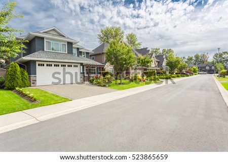 Nicely trimmed and manicured garden in front of a luxury house on a sunny summer day. Street of houses in the suburbs of Canada.