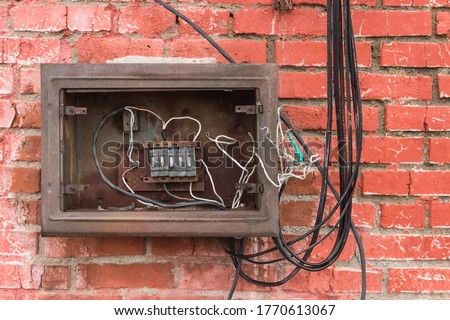 Niche of an old broken electrical panel on the background of an old red brick wall texture