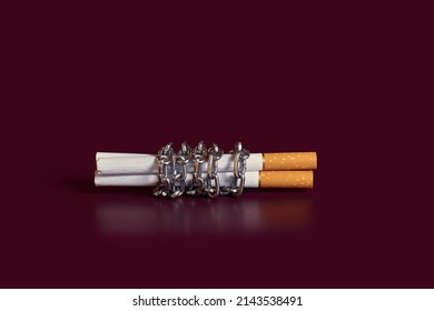 Nicotine addiction. Three cigarettes rewound by a chain on a colored background - Shutterstock ID 2143538491
